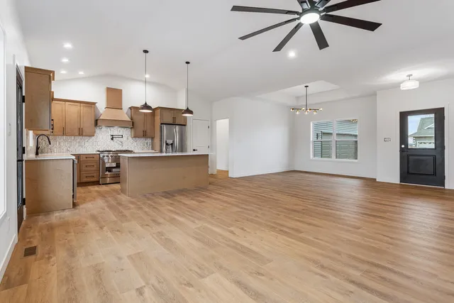 a view of a kitchen with kitchen island a sink wooden floor and stainless steel appliances