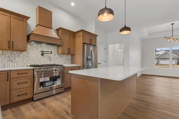 a kitchen with stainless steel appliances granite countertop a sink a stove and a wooden floors
