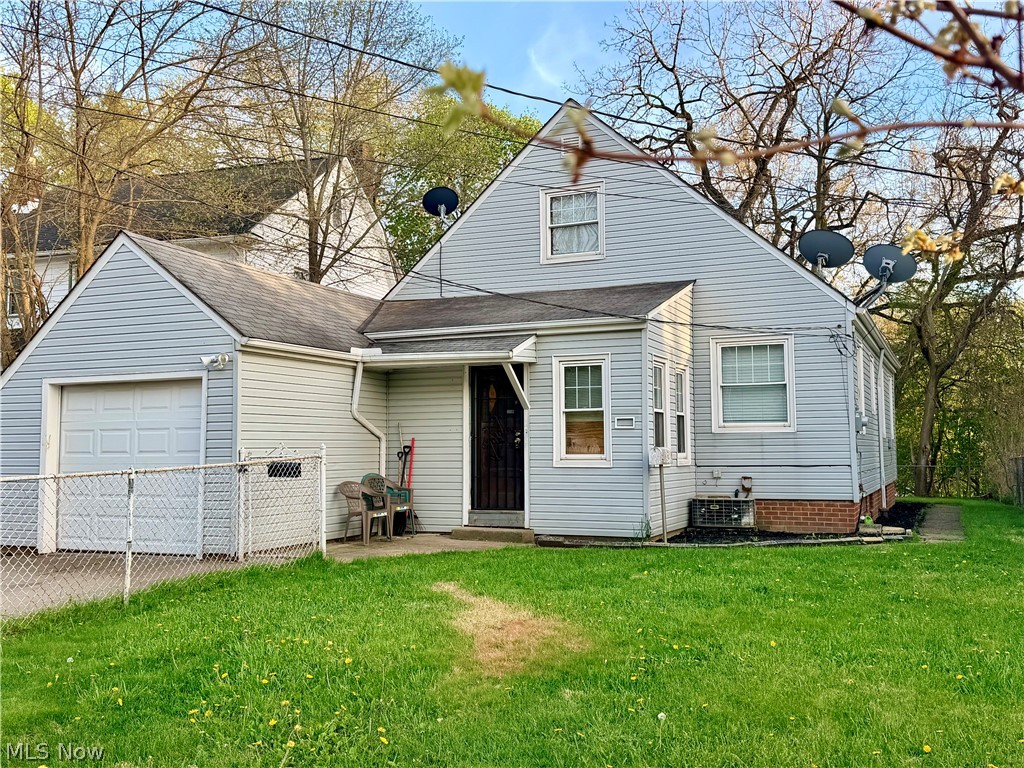 10506 Park Heights Road Cleveland, OH 44104 - Photo 2 of 22 Light blue siding exterior featuring an attached single-car garage with a white panel door, multiple windows with white trim, and a prominent front entry with a dark security door