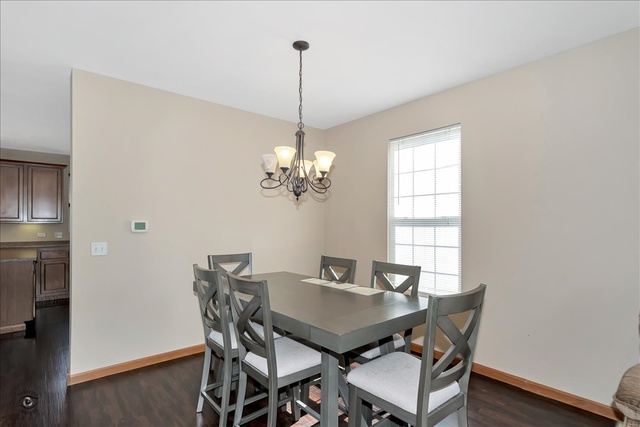 25405 Spring Street Manhattan, IL 60442 - Photo 11 of 36 a view of a dining room with furniture a chandelier and wooden floor