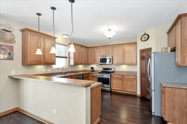 25405 Spring Street Manhattan, IL 60442 - Photo 14 of 36 a kitchen with stainless steel appliances granite countertop a sink a stove a refrigerator and island with wooden floor