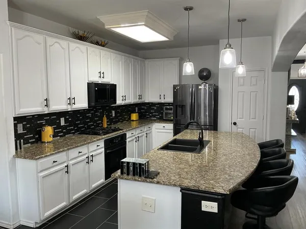 a kitchen with granite countertop a sink a stove and refrigerator