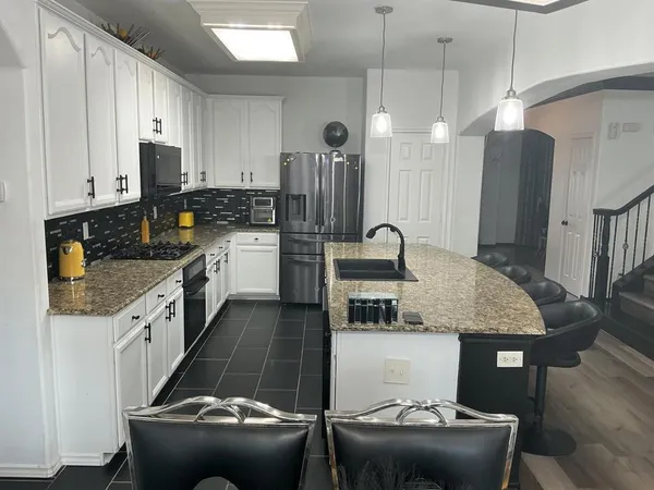 a kitchen with stainless steel appliances granite countertop a sink refrigerator and cabinets