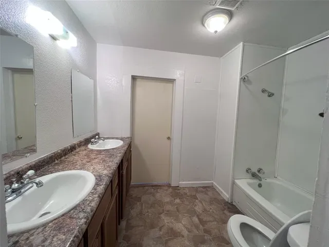 a spacious bathroom with a granite countertop tub sink and mirror