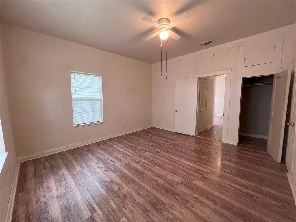 317 Ritchey Street Gainesville, TX 76240 - Photo 10 of 13 Unfurnished bedroom with visible vents, a ceiling fan, dark wood finished floors, and baseboards