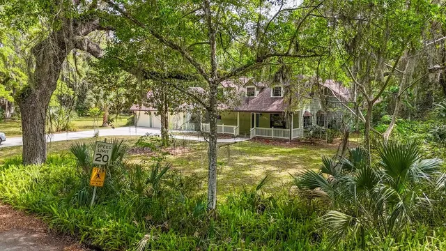a view of a house with large trees and a yard