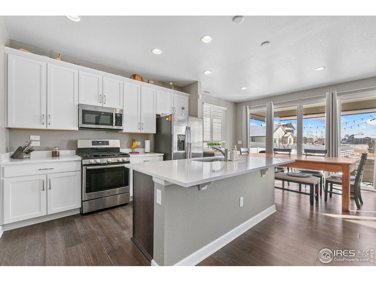 5231 Osbourne Drive Windsor, CO 80550 - Photo 8 of 20 a kitchen with stainless steel appliances granite countertop a stove top oven a sink dishwasher a dining table and chairs with wooden floor