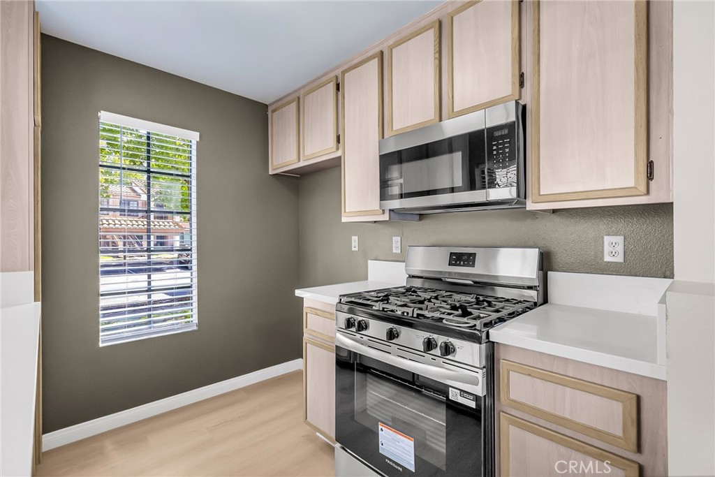 10668 Dabney Drive, Unit 125 San Diego, CA 92126 - Photo 14 of 27 a kitchen with stainless steel appliances granite countertop white cabinets a stove a microwave and a window