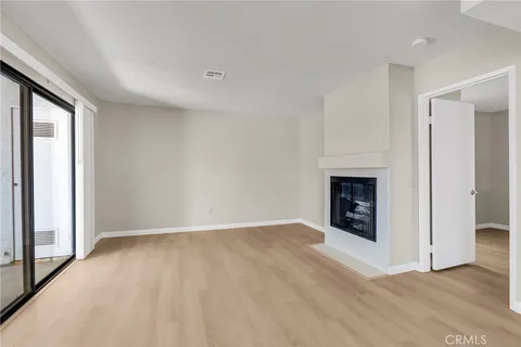 an empty room with kitchen view and fireplace