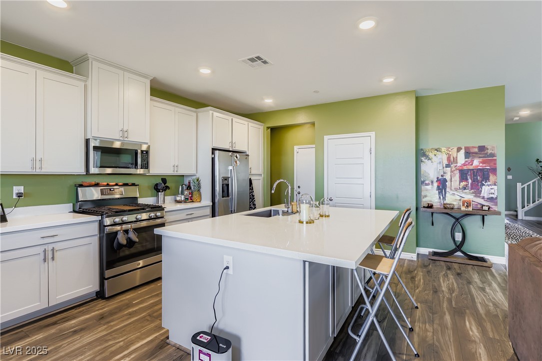 314 Robson Rdg Lane Henderson, NV 89015 - Photo 17 of 64 Kitchen with appliances with stainless steel finishes, a kitchen island with sink, a kitchen bar, dark wood-style floors, and recessed lighting