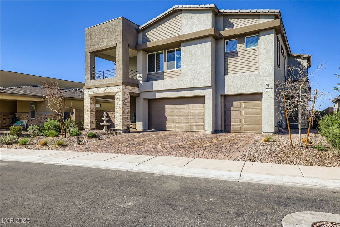 314 Robson Rdg Lane Henderson, NV 89015 - Photo 4 of 64 View of front facade featuring stucco siding, a balcony, an attached garage, and decorative driveway