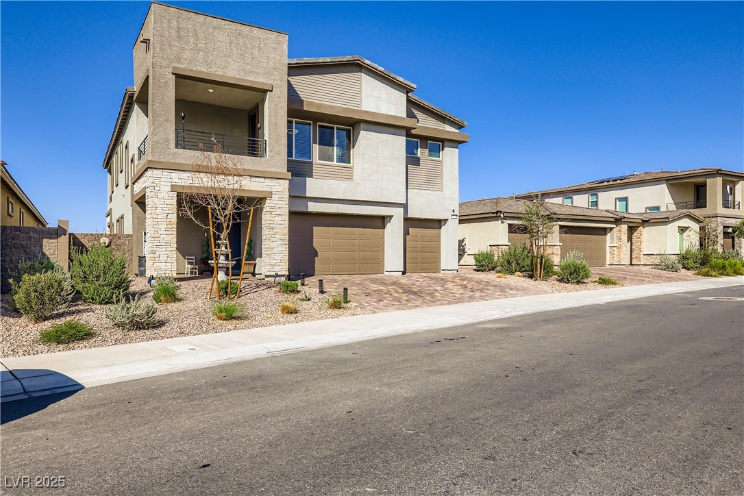 314 Robson Rdg Lane Henderson, NV 89015 - Photo 5 of 64 Contemporary home featuring stone siding, a balcony, stucco siding, decorative driveway, and an attached garage