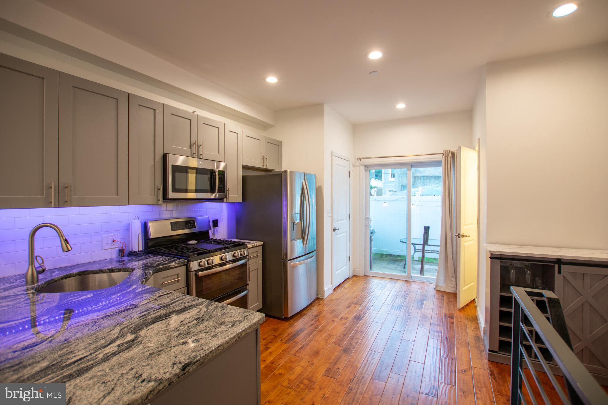 1910 Fernon Street Philadelphia, PA 19145 - Photo 8 of 44 a kitchen with stainless steel appliances granite countertop a refrigerator stove and wooden floor