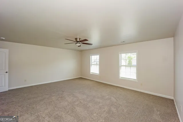an empty room with windows and ceiling fan view