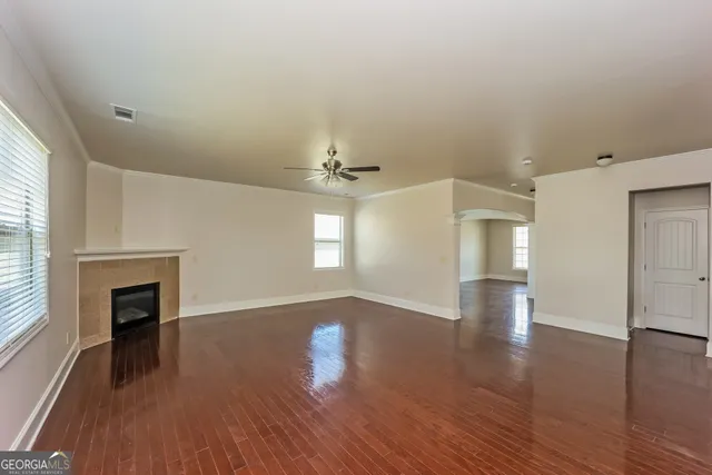 an empty room with wooden floor fireplace and windows