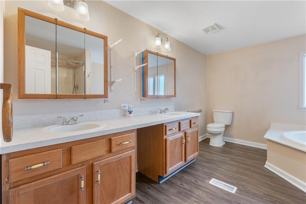 5498 Woodlin Road Lula, GA 30554 - Photo 24 of 40 a spacious bathroom with a double vanity sink mirror and toilet