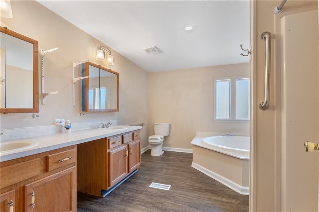 5498 Woodlin Road Lula, GA 30554 - Photo 26 of 40 a bathroom with a double vanity sink toilet and a mirror