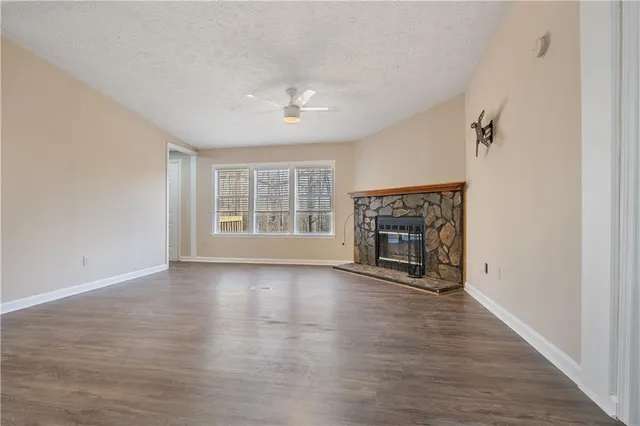 an empty room with wooden floor fireplace and windows