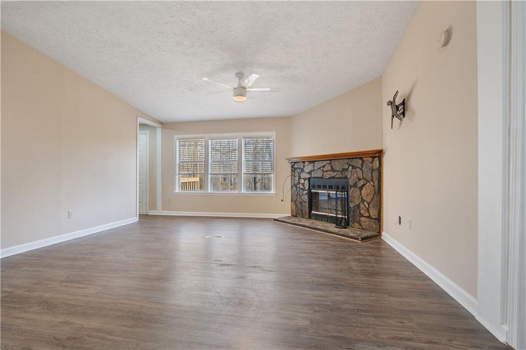 5498 Woodlin Road Lula, GA 30554 - Photo 8 of 40 an empty room with wooden floor fireplace and windows