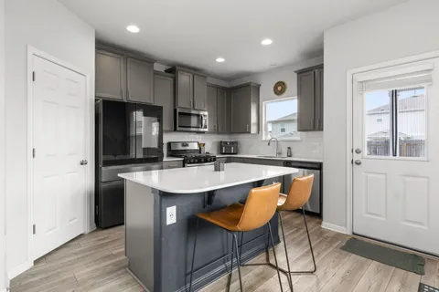 a kitchen with stainless steel appliances granite countertop a sink a stove a refrigerator and island with wooden floor