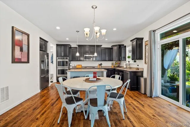 a dining room with stainless steel appliances kitchen island granite countertop a dining table chairs and a oven