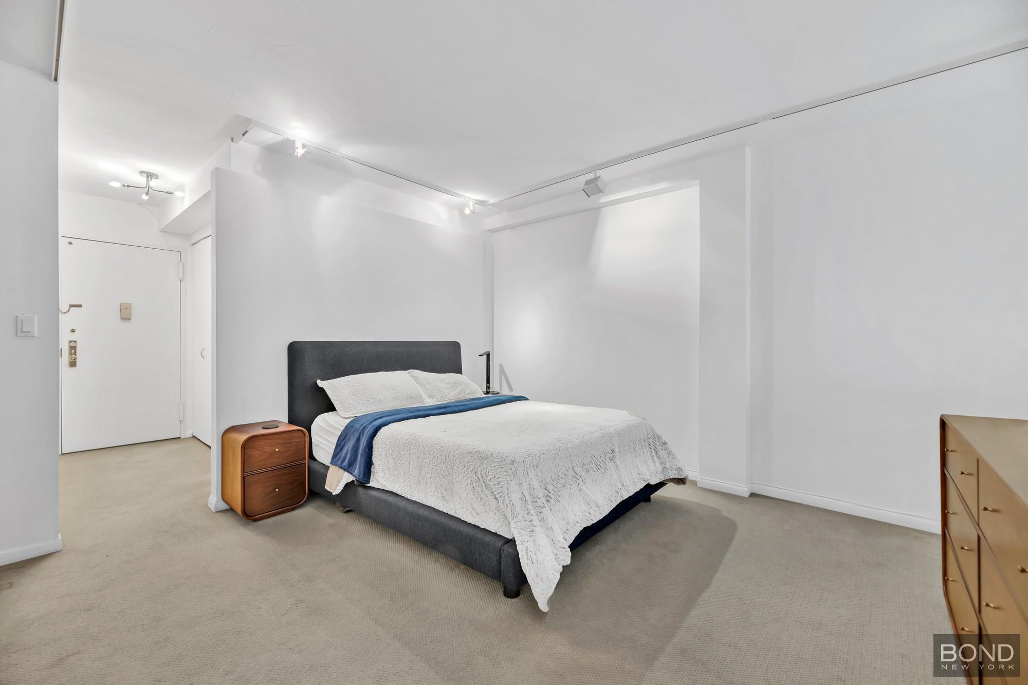 32 East 76th Street, Unit 502602 Manhattan, NY 10021 - Photo 5 of 8 a bedroom with a bed and closet with wooden floor