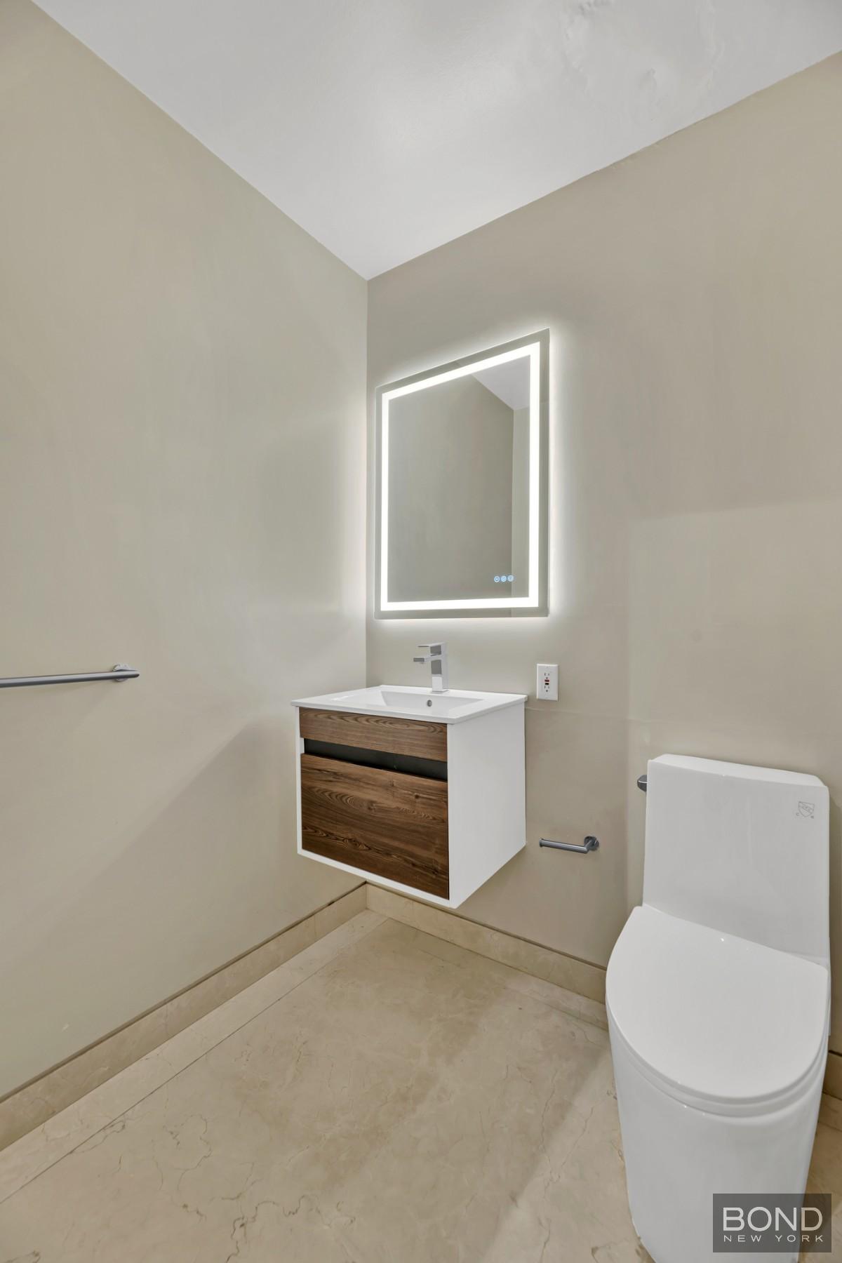 32 East 76th Street, Unit 502602 Manhattan, NY 10021 - Photo 6 of 8 a bathroom with a toilet a sink and mirror