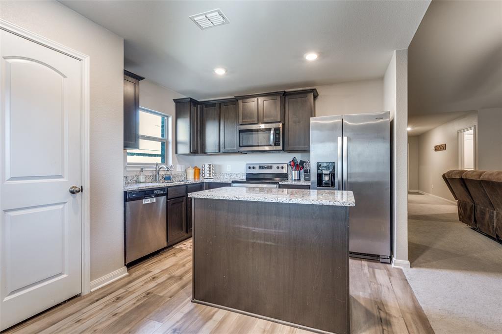 201 Cattlemans Crk Road Newark, TX 76071 - Photo 8 of 25 a kitchen with kitchen island a counter top space cabinets and stainless steel appliances