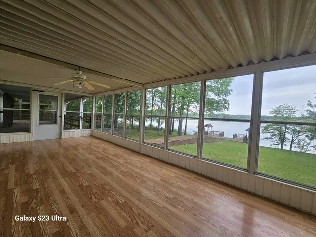 a view of empty room with wooden floor and floor to ceiling window