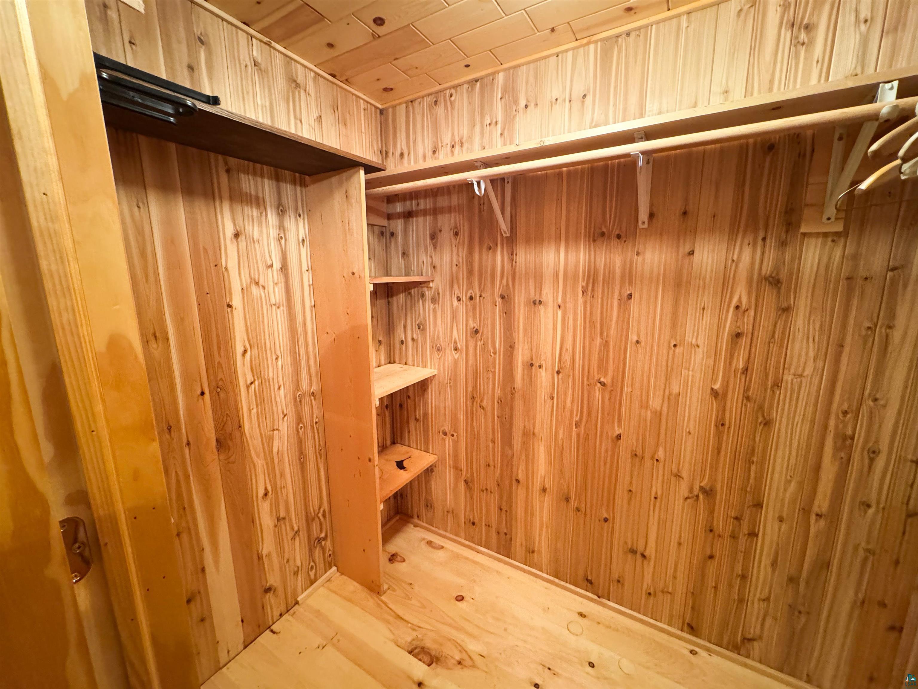 465 South Gunflint Lake Road Grand Marais, MN 55604 - Photo 43 of 46 Wood-paneled closet featuring a built-in shelving unit, overhead storage shelf, and clothing rod