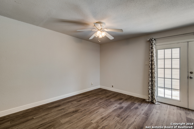 4838 Aspen Wood Kirby, TX 78219 - Photo 3 of 11 an empty room with wooden floor chandelier fan and windows
