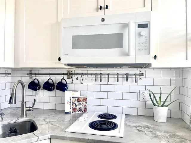 a kitchen with sink a refrigerator and white cabinets