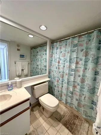 a bathroom with a sink a toilet a mirror and shower curtain