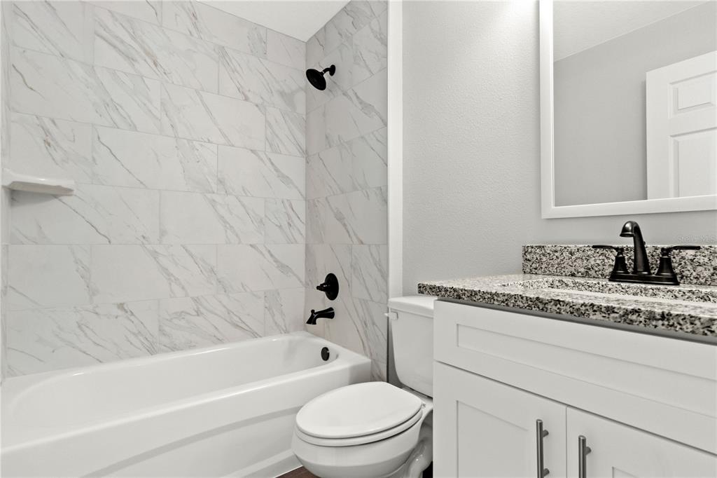 605 Abarth Avenue Sebring, FL 33872 - Photo 11 of 28 a bathroom with a granite countertop bathtub shower sink vanity and toilet