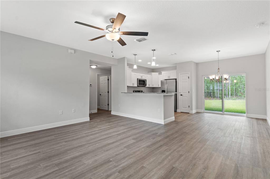 605 Abarth Avenue Sebring, FL 33872 - Photo 2 of 28 a view of an empty room with wooden floor and a kitchen