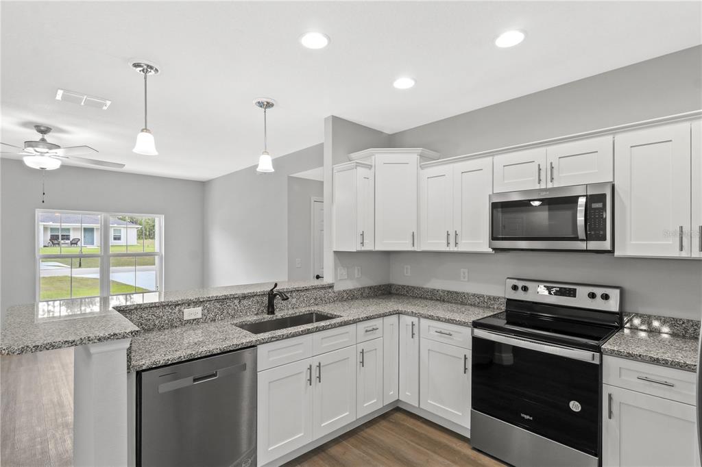605 Abarth Avenue Sebring, FL 33872 - Photo 27 of 28 a kitchen with stainless steel appliances granite countertop a sink and a stove top oven with granite countertops