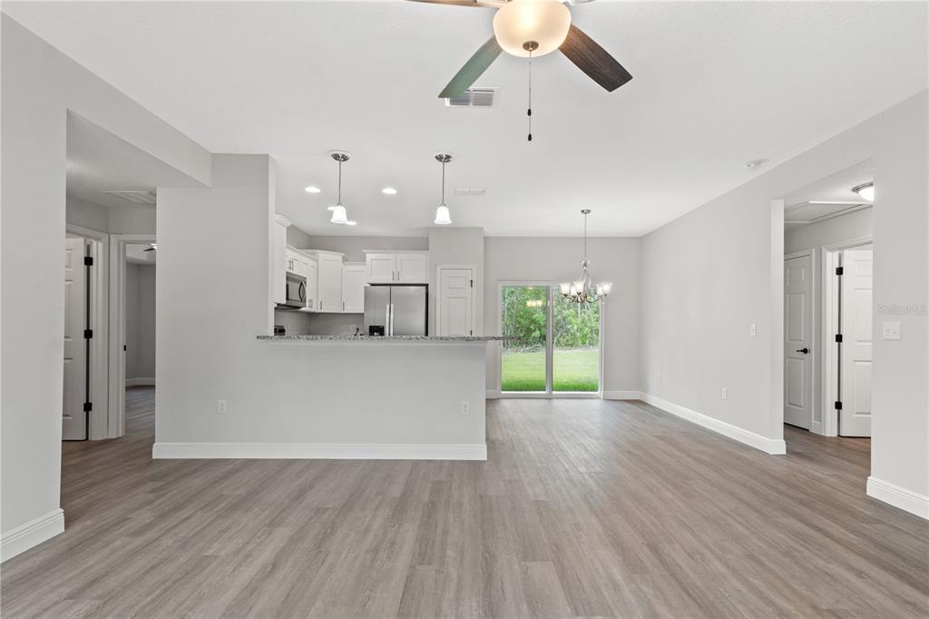 605 Abarth Avenue Sebring, FL 33872 - Photo 3 of 28 a view of an empty room and kitchen with wooden floor