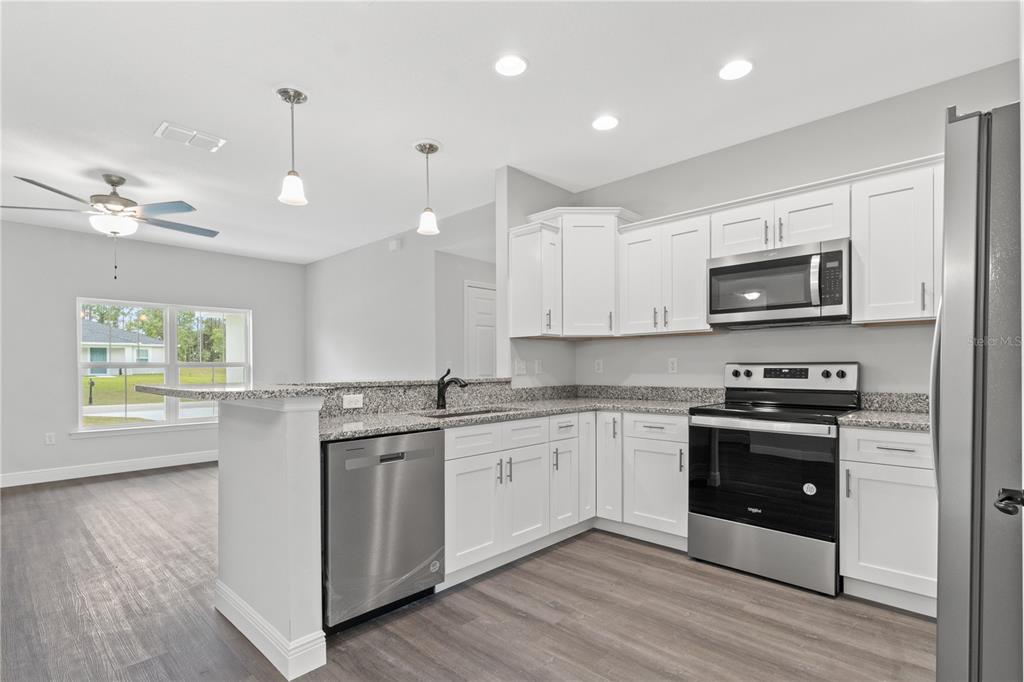 605 Abarth Avenue Sebring, FL 33872 - Photo 6 of 28 a kitchen with stainless steel appliances granite countertop a stove a sink and a microwave
