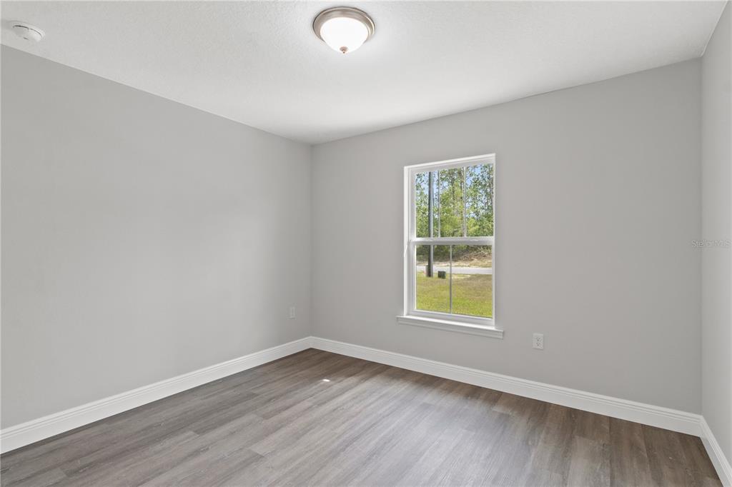 605 Abarth Avenue Sebring, FL 33872 - Photo 9 of 28 an empty room with wooden floor and a window