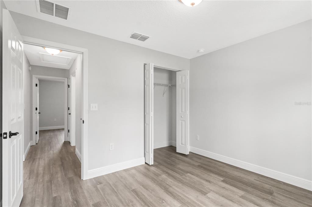 605 Abarth Avenue Sebring, FL 33872 - Photo 10 of 28 an empty room with wooden floor and a bathroom