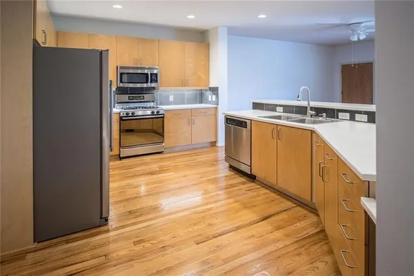 a kitchen with stainless steel appliances a sink a stove and a wooden floors