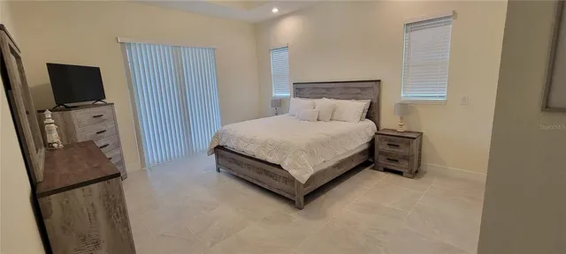 a bedroom with a bed flat screen tv and a lamp on the dresser
