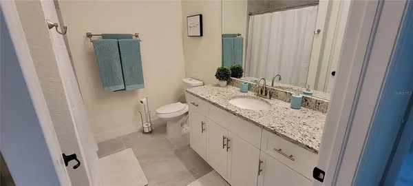 a bathroom with a granite countertop sink toilet and mirror