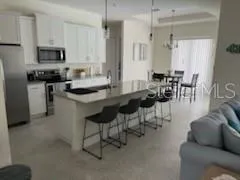 a kitchen with stainless steel appliances kitchen island granite countertop a table chairs microwave and sink
