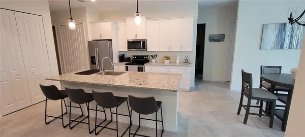 a kitchen with granite countertop a table chairs refrigerator and microwave