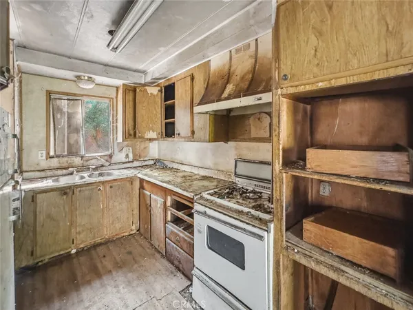 a kitchen with stainless steel appliances granite countertop a refrigerator a sink dishwasher a stove and white countertops with wooden floor