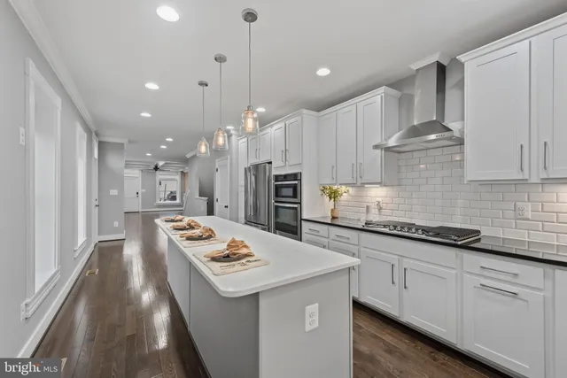 a kitchen with stainless steel appliances kitchen island granite countertop a sink stove and white cabinets