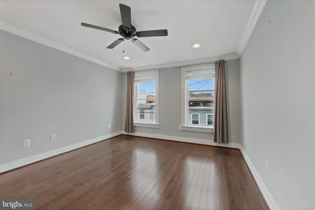 a view of an empty room with a window and wooden floor