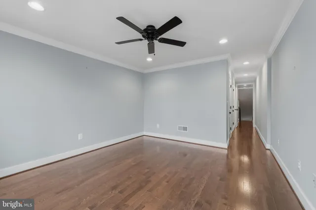an empty room with wooden floor and ceiling fan
