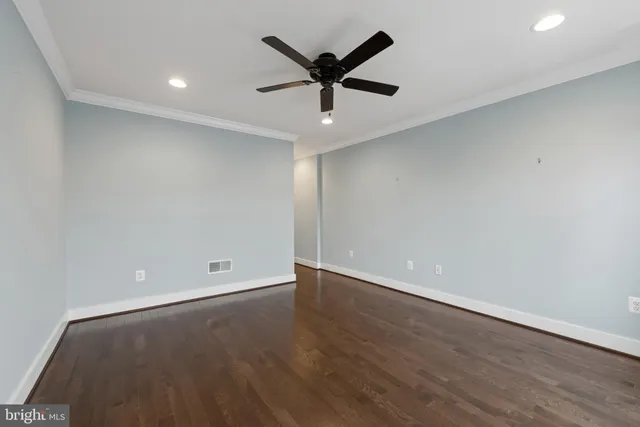 an empty room with wooden floor and ceiling fan